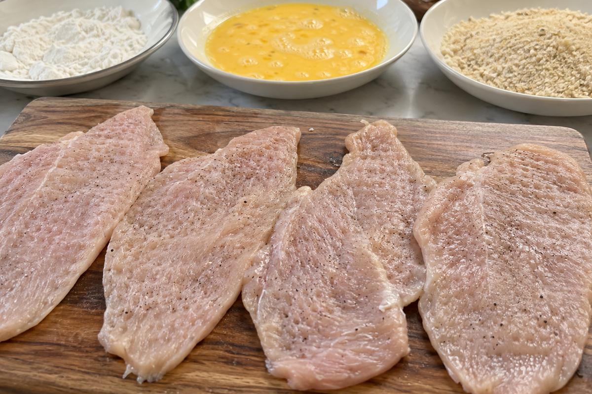 Pounded chicken breasts ready for breading process.